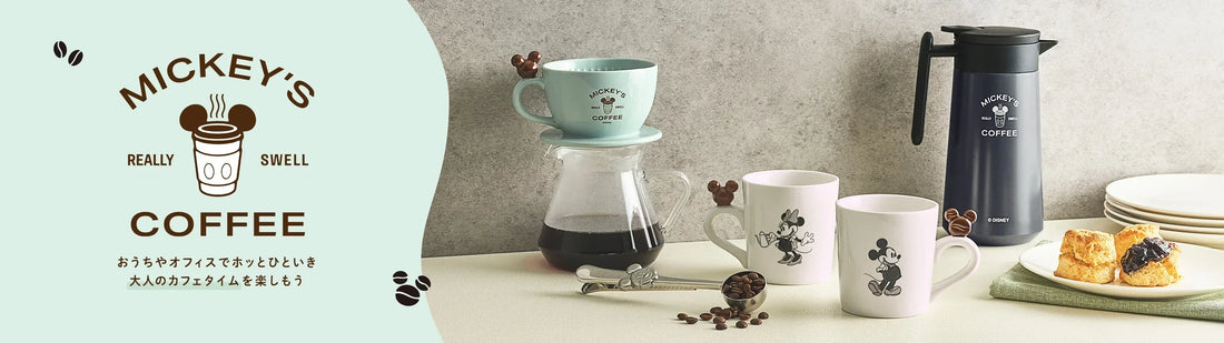 Disney Store Japan Life with Cafe collection banner. Features a mint green Mickey Mouse coffee dripper, glass server, white Mickey and Minnie mugs with biscuit-shaped handles, and a navy blue stainless steel coffee pot.