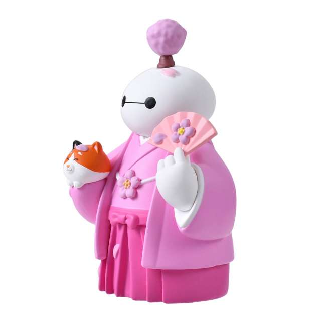 An adorable figure of Baymax from Big Hero 6 dressed in a traditional pink kimono and hakama for the cherry blossom season. Baymax holds a pink fan with a flower design in one hand and cradles Mochi the cat (also smiling) in the other arm. A small cherry blossom tree sprouts from Baymax's head. The setting is a festive pink sakura background.