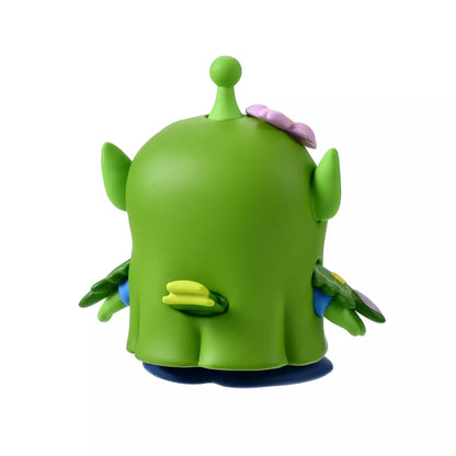 A whimsical figure of a Little Green Man (Alien) disguised as a Japanese Bush Warbler (Uguisu). The Alien is wearing a green bird costume with yellow beak details and blue accents on the wings. Pink cherry blossom flowers decorate the costume's head and beak. The figure stands in front of a scenic pink background with sakura motifs.