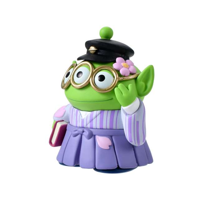 A Disney Store Japan exclusive figure of a Little Green Man (Alien) from Toy Story. The character is dressed in a traditional Japanese purple striped hakama and wears a black student cap. It poses with a book in one hand and touches its glasses with the other. The figure is set against a pink striped background with falling cherry blossom petals.