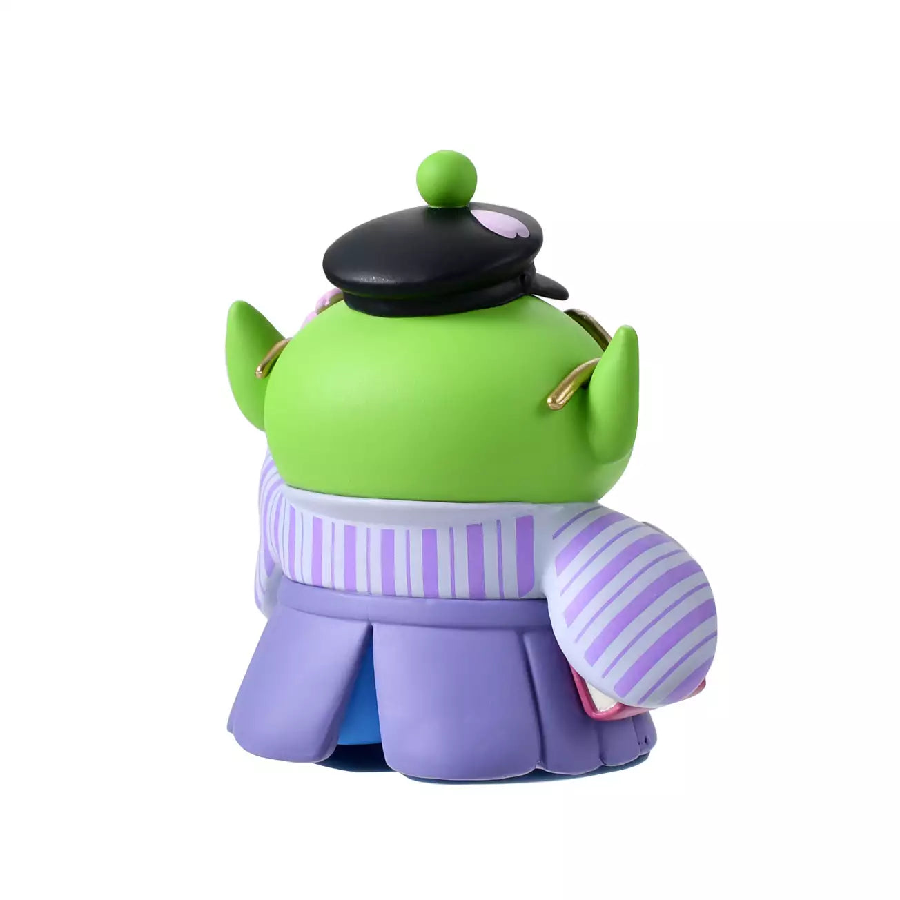 A Disney Store Japan exclusive figure of a Little Green Man (Alien) from Toy Story. The character is dressed in a traditional Japanese purple striped hakama and wears a black student cap. It poses with a book in one hand and touches its glasses with the other. The figure is set against a pink striped background with falling cherry blossom petals.