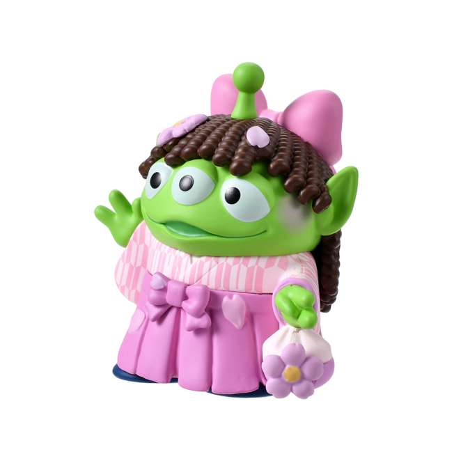 A cute collectible figure of a Little Green Man (Alien) wearing a pink wig with brown pigtails and a traditional pink hakama kimono. The character holds a small flower-shaped purse and waves with one hand. The backdrop features a pink striped pattern with delicate cherry blossom illustrations.