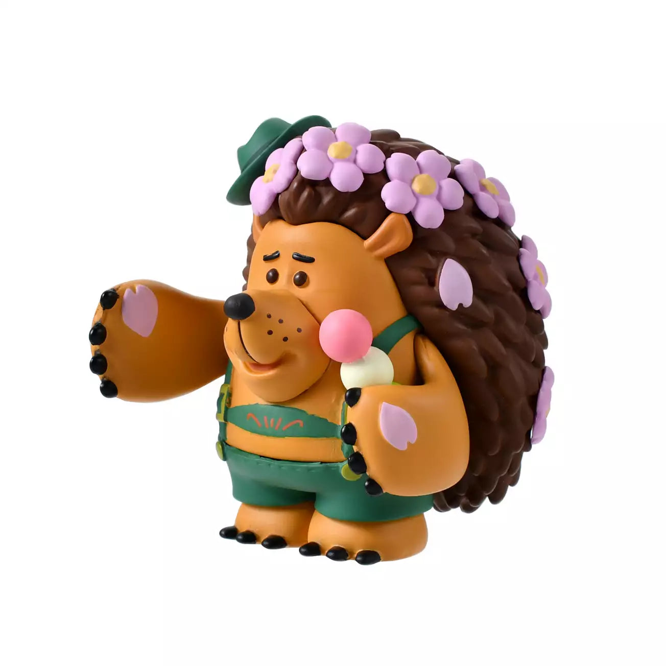 A figure of Mr. Pricklepants from Toy Story 3 enjoying a spring picnic. The hedgehog wears green lederhosen and a small green hat. He holds a 'Hanami Dango' (a three-colored sweet dumpling) in one hand and has a crown of pink cherry blossoms on his head. The background is pink with falling sakura petals.