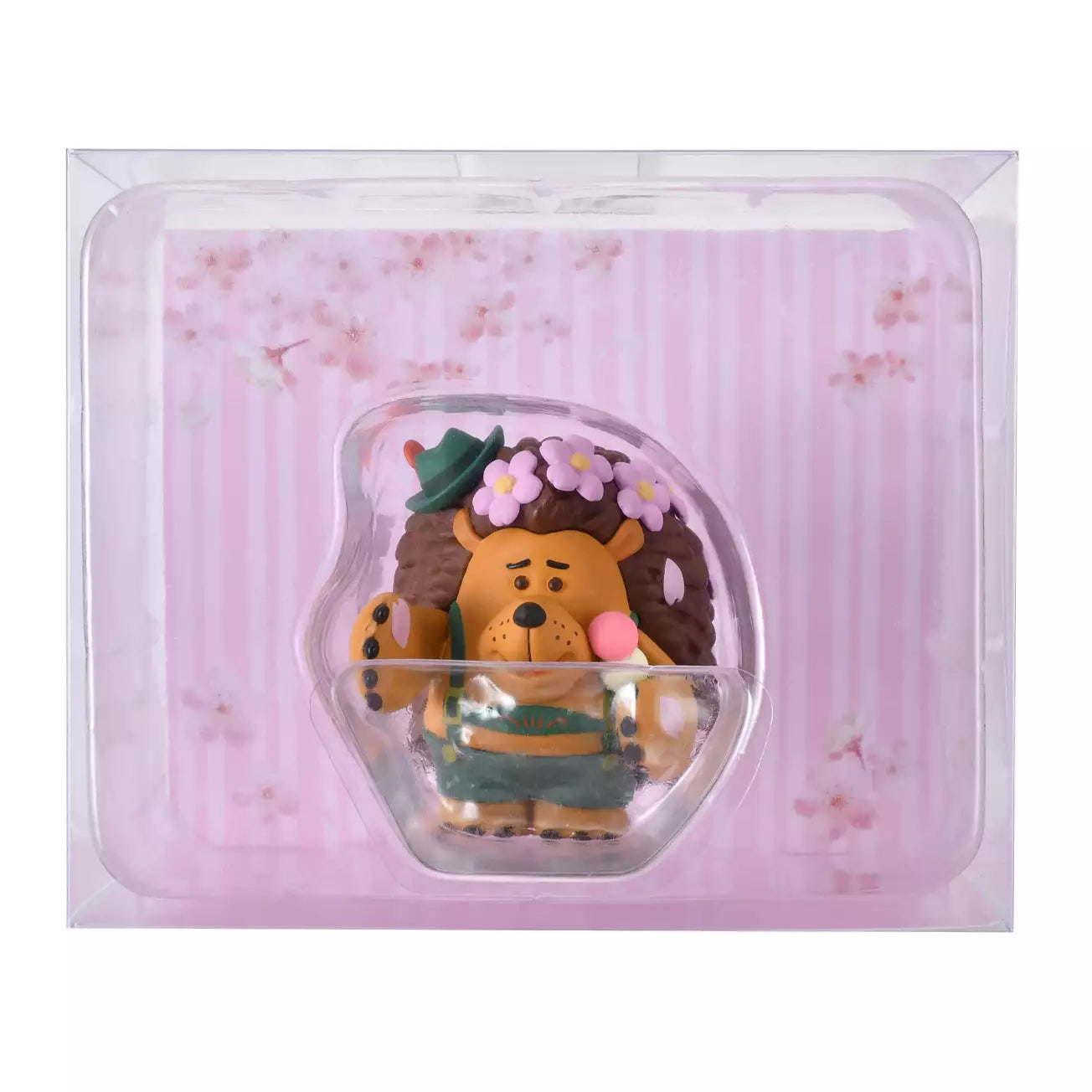 A figure of Mr. Pricklepants from Toy Story 3 enjoying a spring picnic. The hedgehog wears green lederhosen and a small green hat. He holds a 'Hanami Dango' (a three-colored sweet dumpling) in one hand and has a crown of pink cherry blossoms on his head. The background is pink with falling sakura petals.