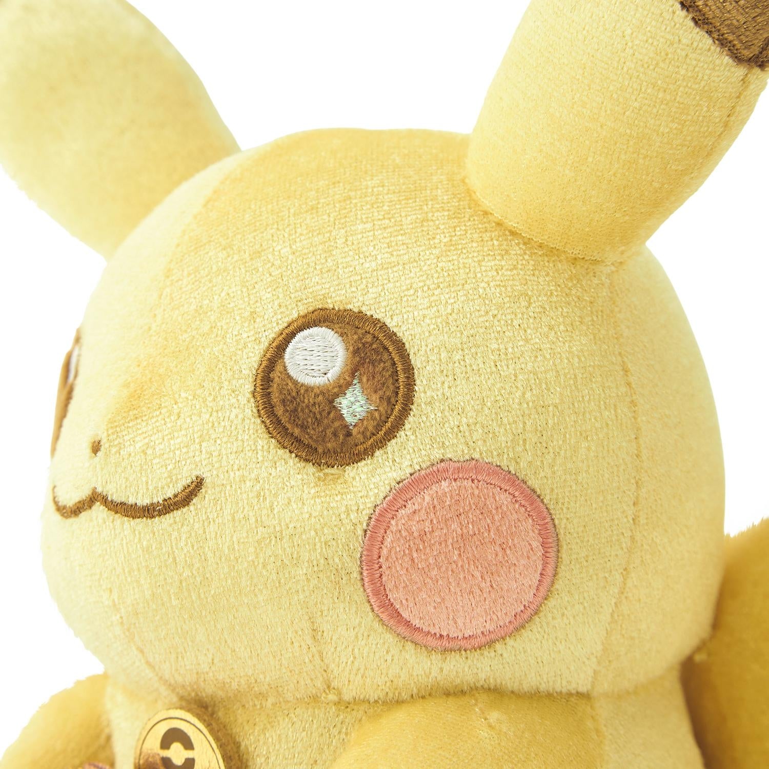 Close-up of the exclusive Pokémon 30th Anniversary Pikachu plush, showing the special golden 'Since 1996' woven tag and delicate glitter fabric.