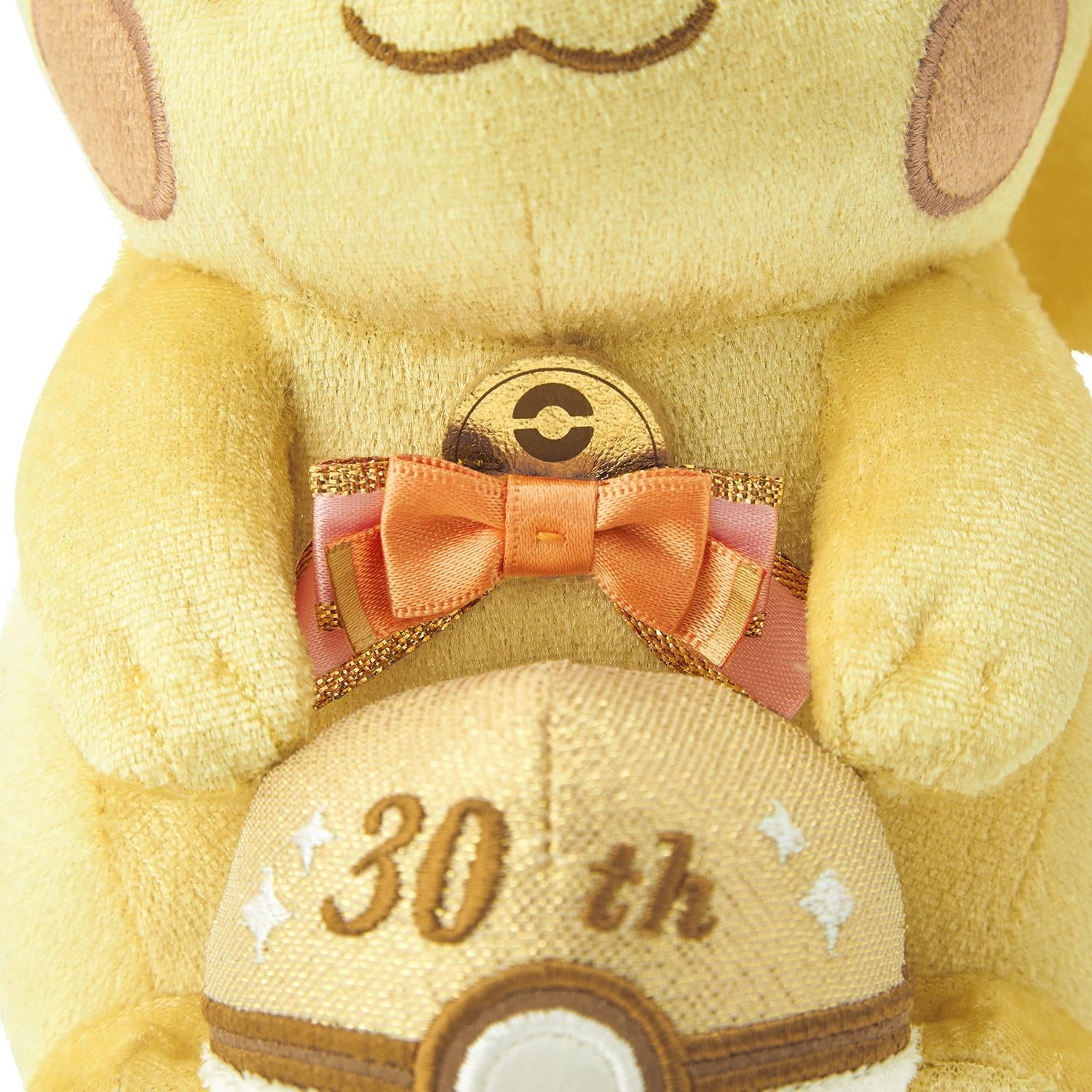 Close-up of the exclusive Pokémon 30th Anniversary Pikachu plush, showing the special golden 'Since 1996' woven tag and delicate glitter fabric.