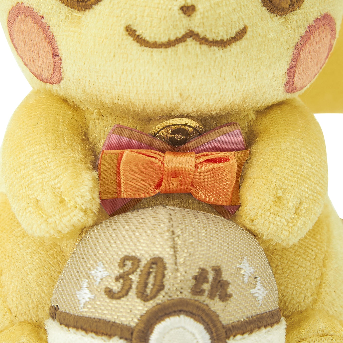 Close-up of the exclusive Pokémon 30th Anniversary Pikachu keychain, showing the special golden 'Since 1996' woven tag and delicate glitter fabric.
