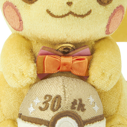 Close-up of the exclusive Pokémon 30th Anniversary Pikachu keychain, showing the special golden 'Since 1996' woven tag and delicate glitter fabric.