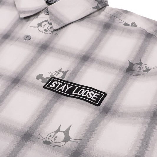 A grey and white plaid button-down shirt from the USJ UNIVRS collection with an all-over print of Felix the Cat's face and a black patch that says 'STAY LOOSE'.