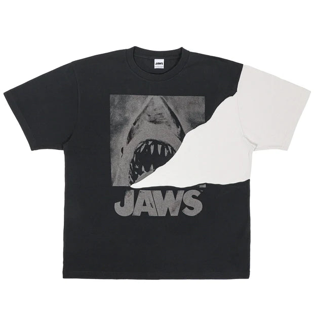 A black and white color-blocked t-shirt from the USJ UNIVRS collection. The shirt features a large graphic of the shark from Jaws with the word 'JAWS' printed below it.