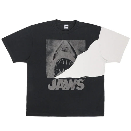 A black and white color-blocked t-shirt from the USJ UNIVRS collection. The shirt features a large graphic of the shark from Jaws with the word 'JAWS' printed below it.