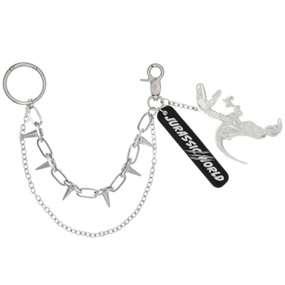 A silver metal keychain from the USJ UNIVRS collection featuring a dinosaur skeleton charm, a black tag that says 'JURASSIC WORLD', and a chain with small spikes.