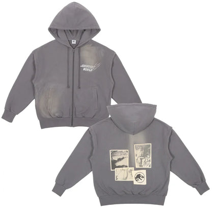 A grey zip-up hoodie from the USJ UNIVRS collection with a subtle graphic of a dinosaur scratching its claws and the text 'JURASSIC WORLD' on the front. The back features four vintage comic panels of dinosaurs.