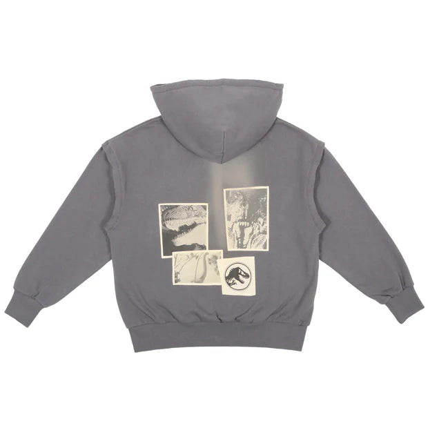A grey zip-up hoodie from the USJ UNIVRS collection with a subtle graphic of a dinosaur scratching its claws and the text 'JURASSIC WORLD' on the front. The back features four vintage comic panels of dinosaurs.